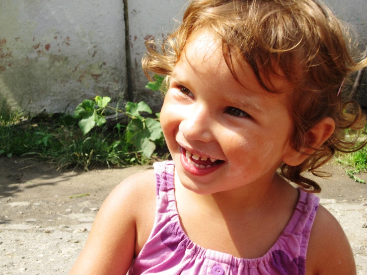 a little girl smiling with a toothbrush in her mouth