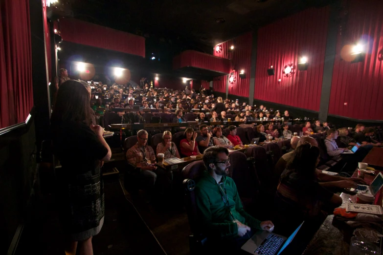 people in an auditorium watching a film on their lap tops