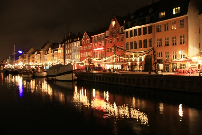 a night view of the city and water with many buildings at the side