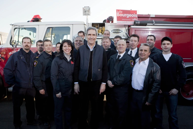 an old fireman in a suit stands with a group of men