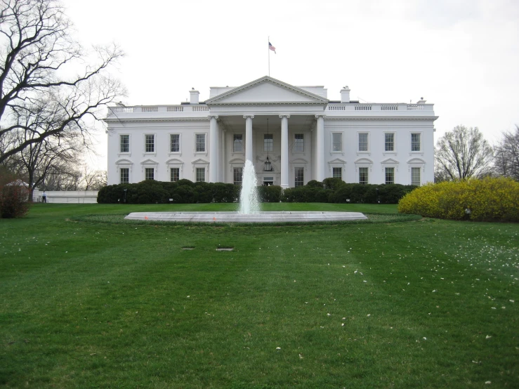 there is a white building with a fountain in front of it