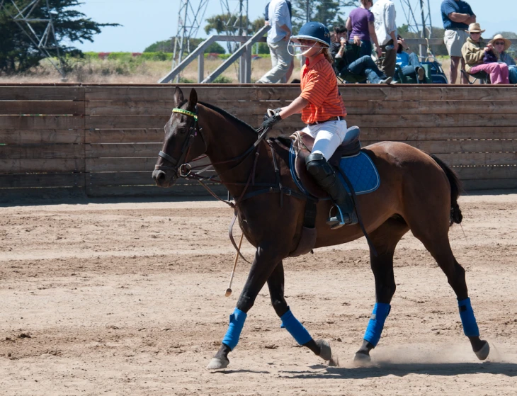 a child is riding a horse while several people watch