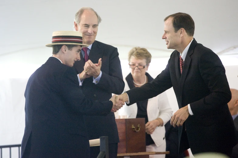 two men shaking hands with other people clapping