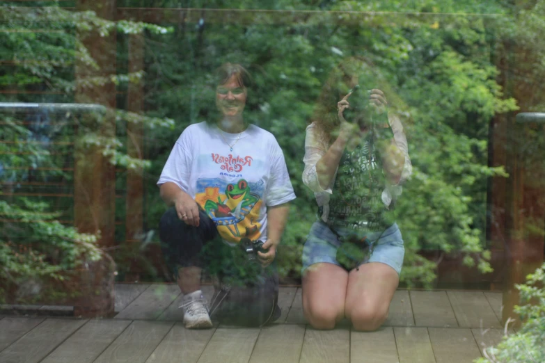 two young women sitting in front of a mirrored door