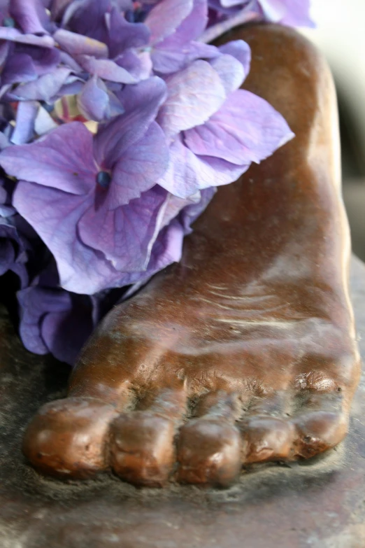 an interesting foot sculpture with purple flowers on it