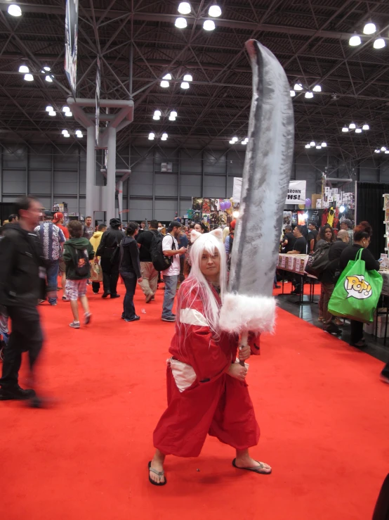 a person in a costume holding a large knife in a room with other people