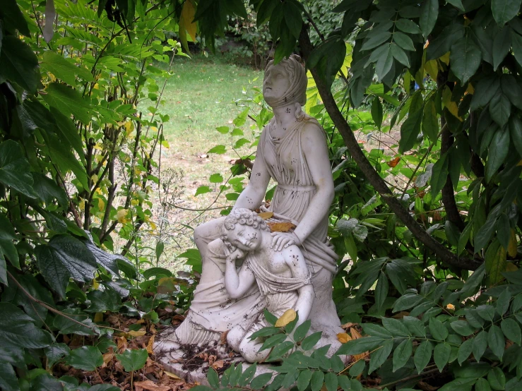 a small statue sitting under some trees in the woods