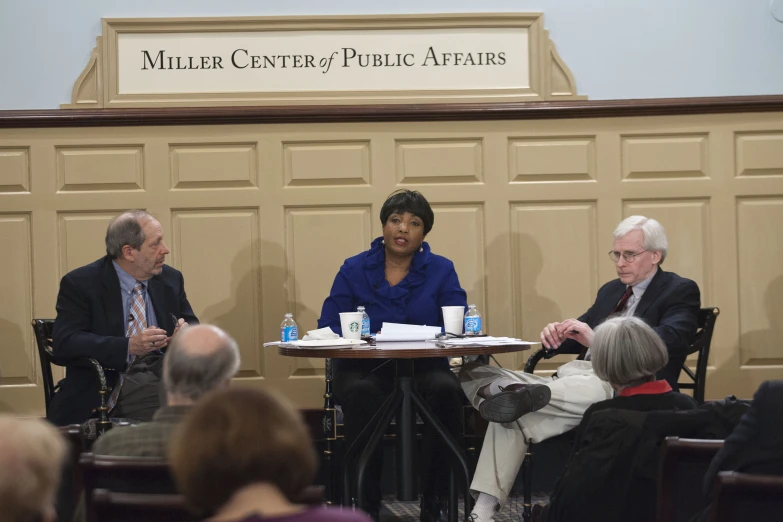 a woman sits at a table in front of three other men