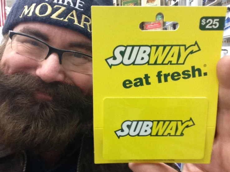 a man is holding up a yellow subway sign