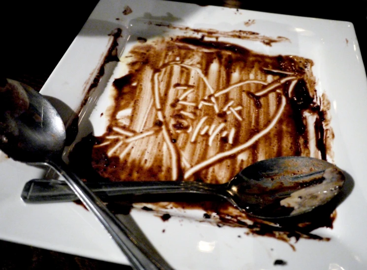 a square plate topped with cake covered in chocolate