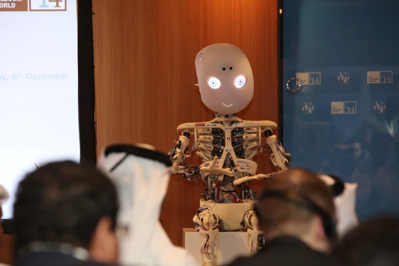 an artificial robot is standing in front of people in an auditorium