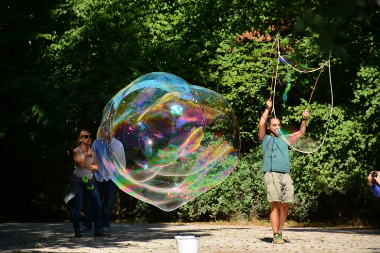 people are watching two men play with soap bubbles in the park