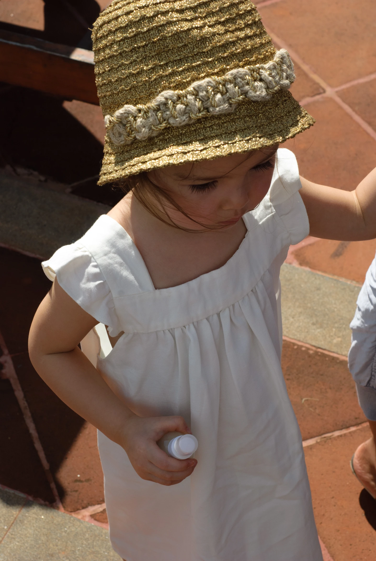 a small girl in a white dress and straw hat