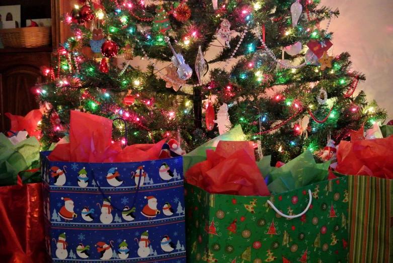 a close up of three bags with presents near a christmas tree