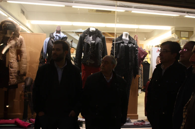 several men are standing in front of suits and jackets