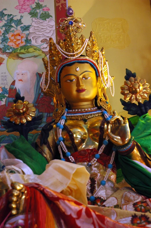 a statue of buddha in gold with jewelry on display