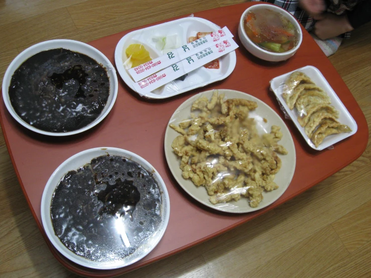 a tray holds three plates and three bowls filled with food