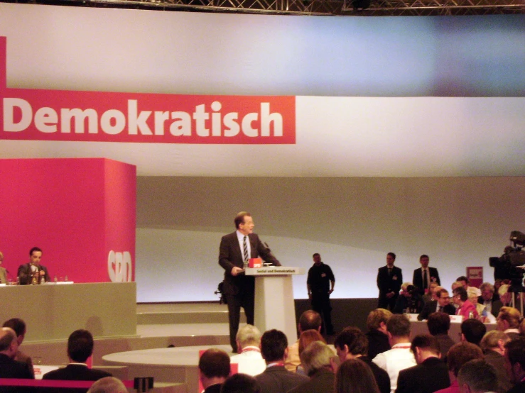 two men and a woman talking on stage at an event