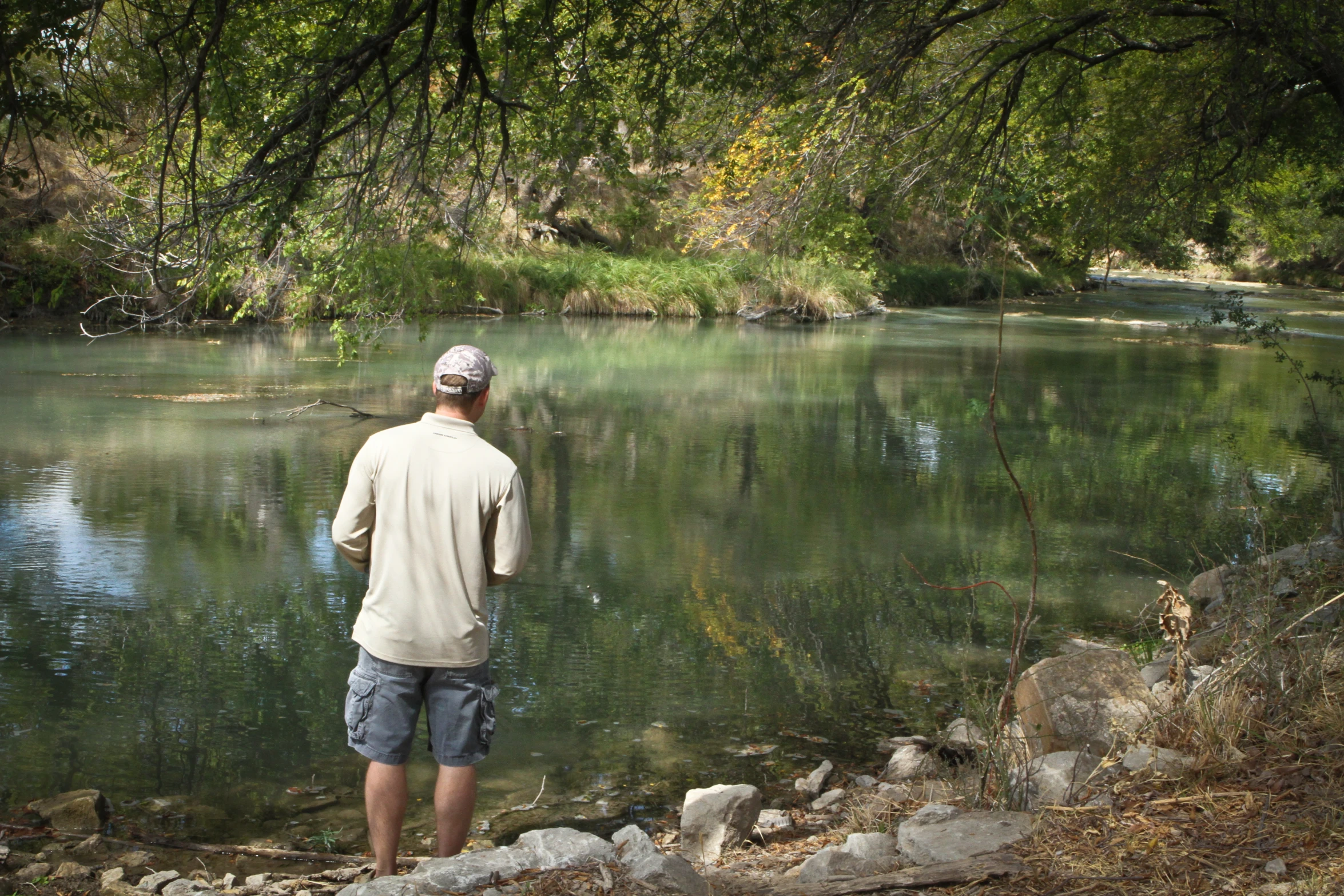 a man standing at the edge of a stream watching