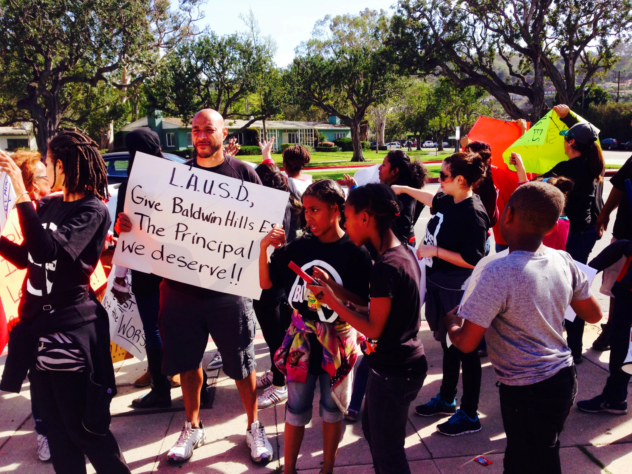 a man standing in front of an outdoor crowd holding a sign