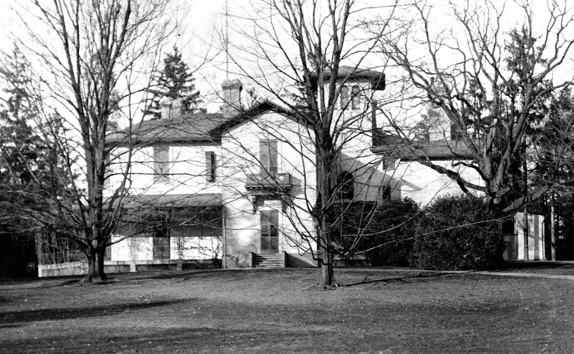 a black and white image of a large house surrounded by trees