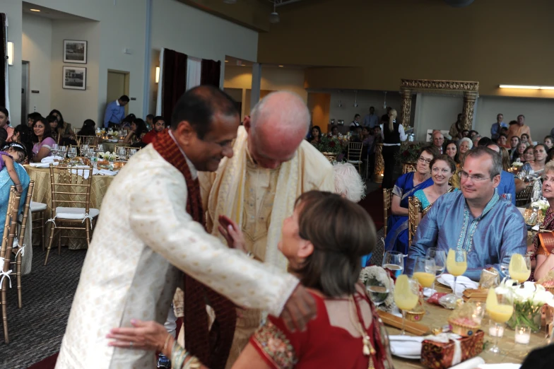 a couple dancing at a wedding with people seated at tables