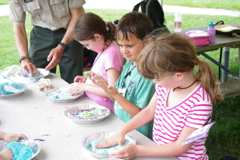 little girls are making art work using paper plates