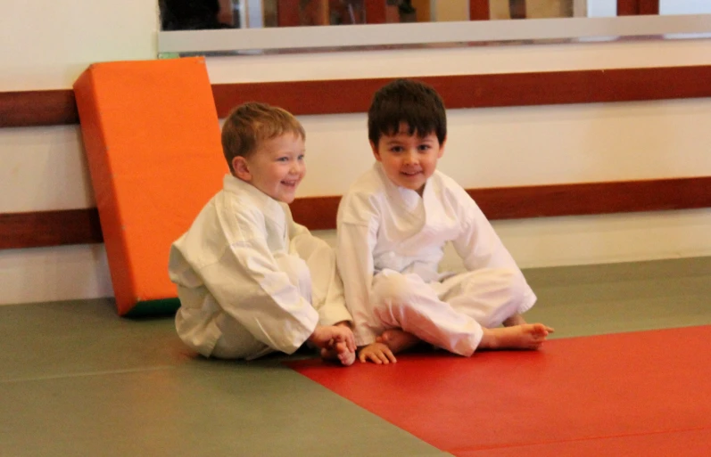 two s sitting on a mat and smiling