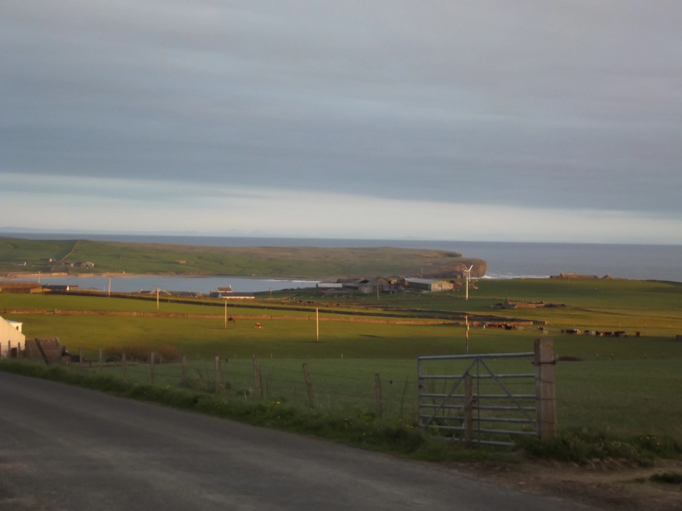 a rural road runs by some farm houses and large fields