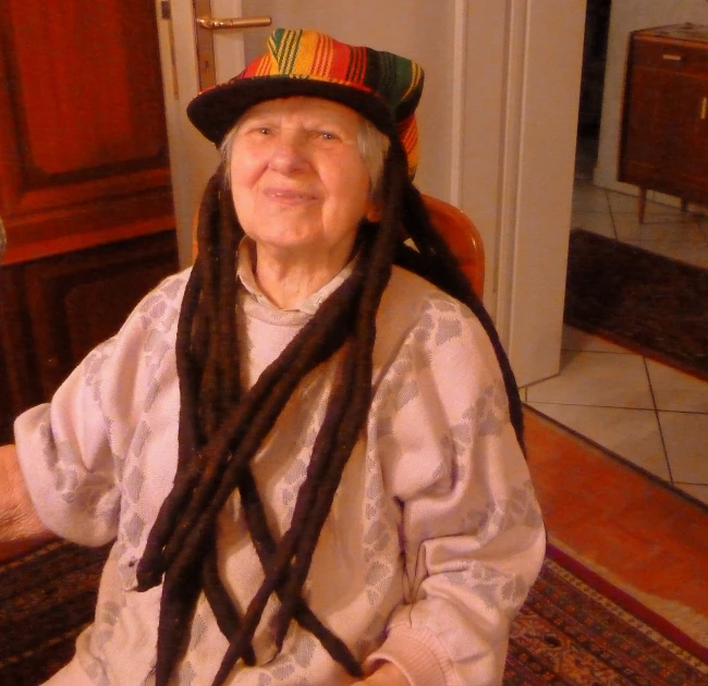 an older woman with long dreadlocks on sitting on a red carpet