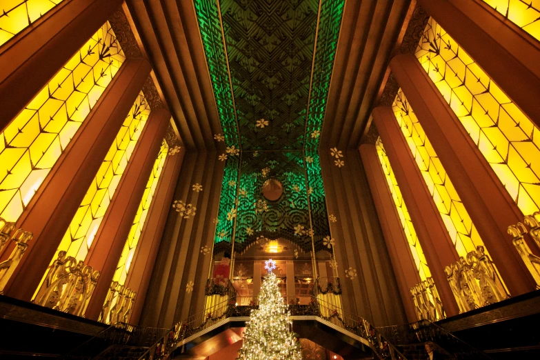 an indoor christmas tree in a lobby surrounded by colorful lights