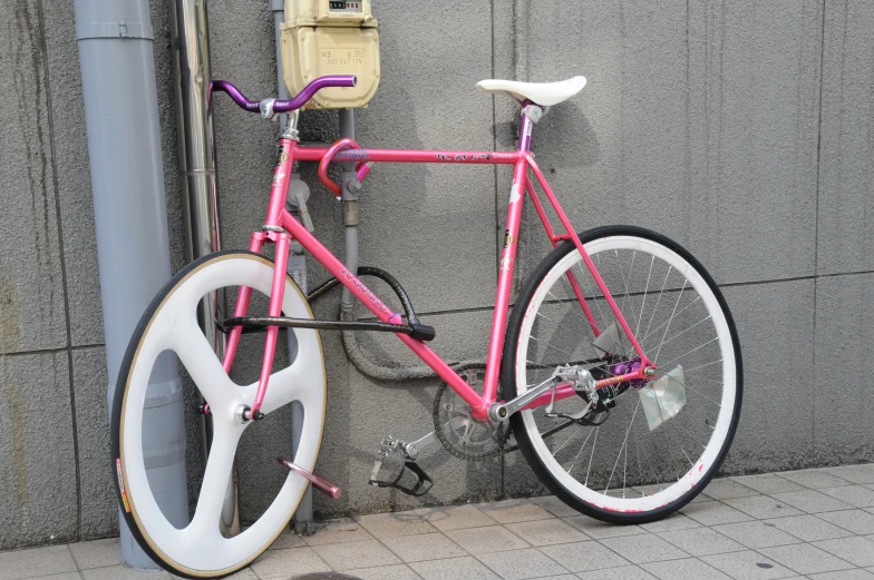 the pink bike is leaning against a meter