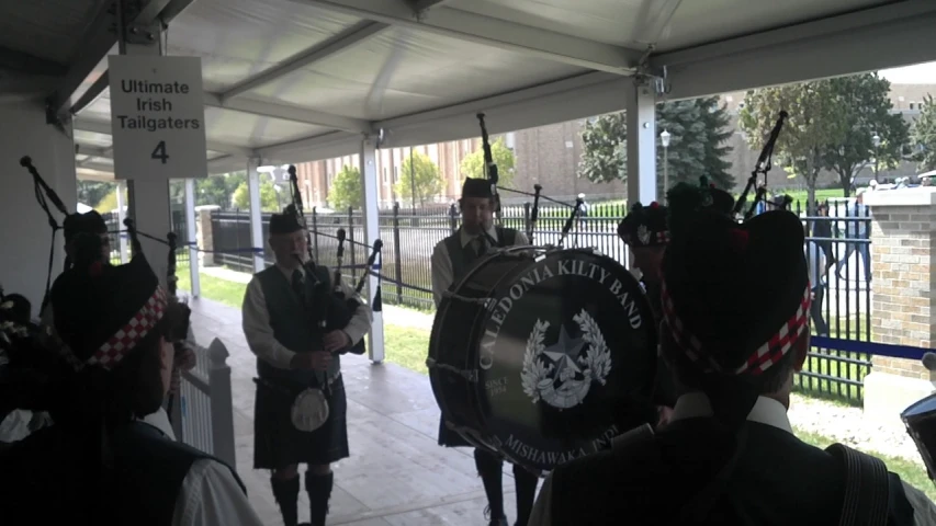 two men wearing kilts playing the bagpipes in front of people