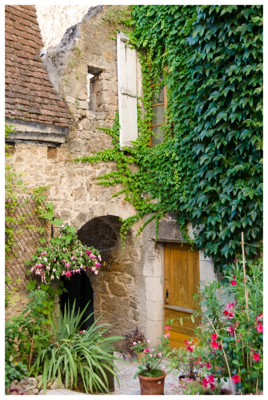 an old stone building surrounded by flowers and plants