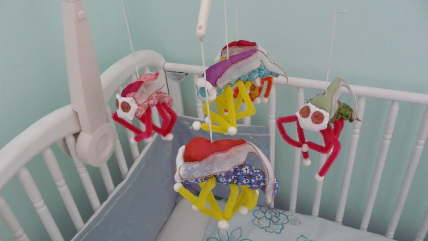 a crib with three mobile puppets hanging from the sides