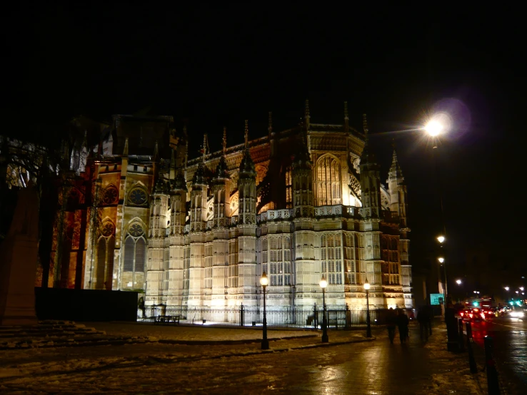 people walking past an old building at night