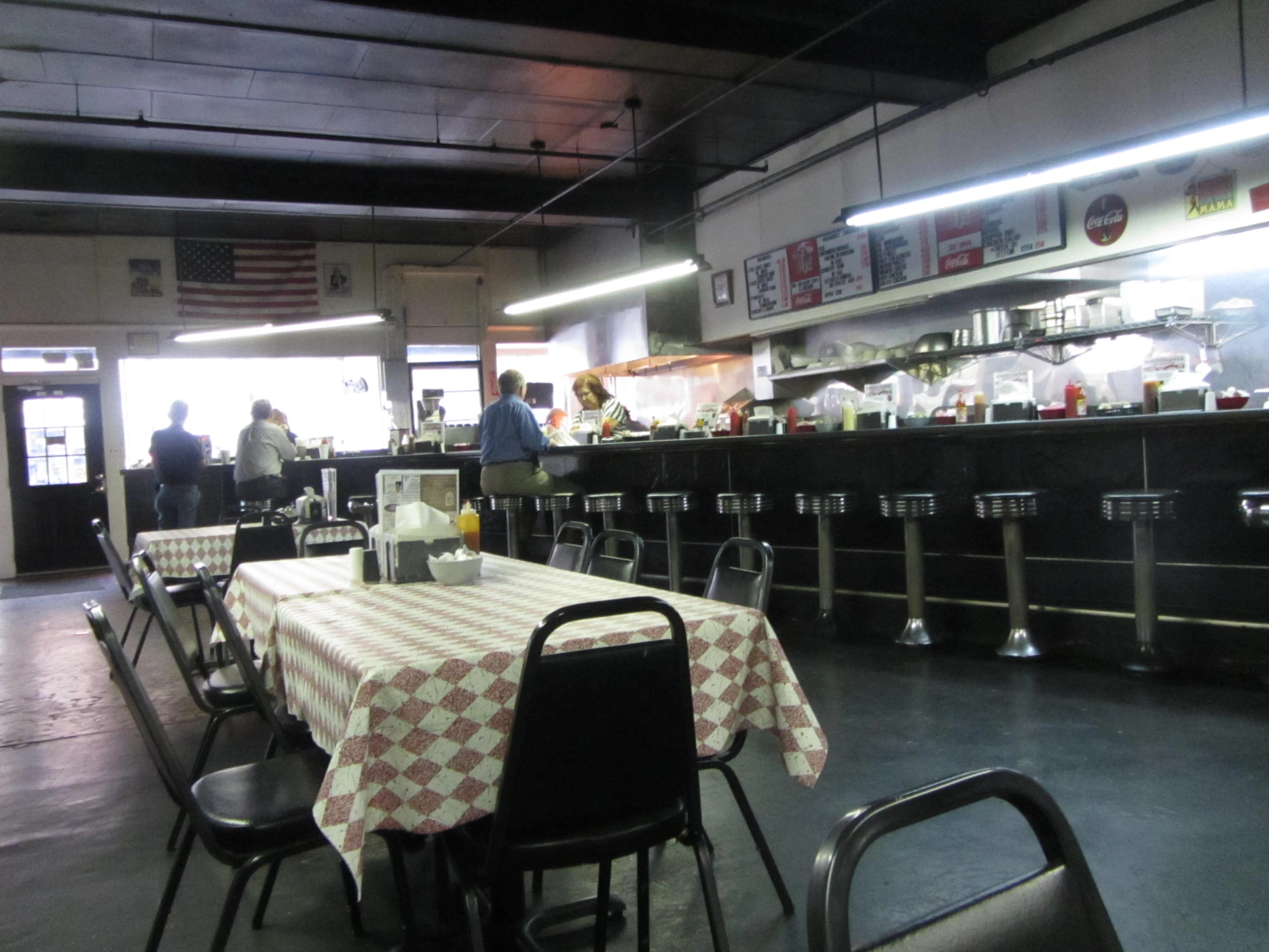 an empty restaurant with two people standing in front of the counters