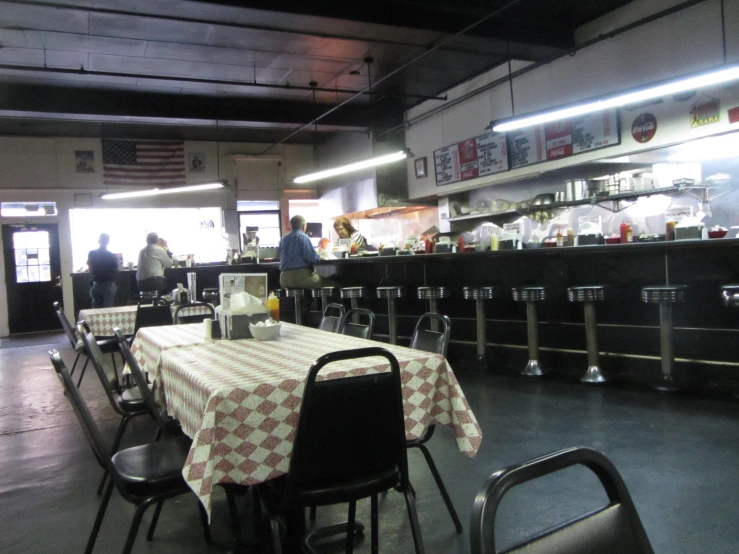 an empty restaurant with two people standing in front of the counters