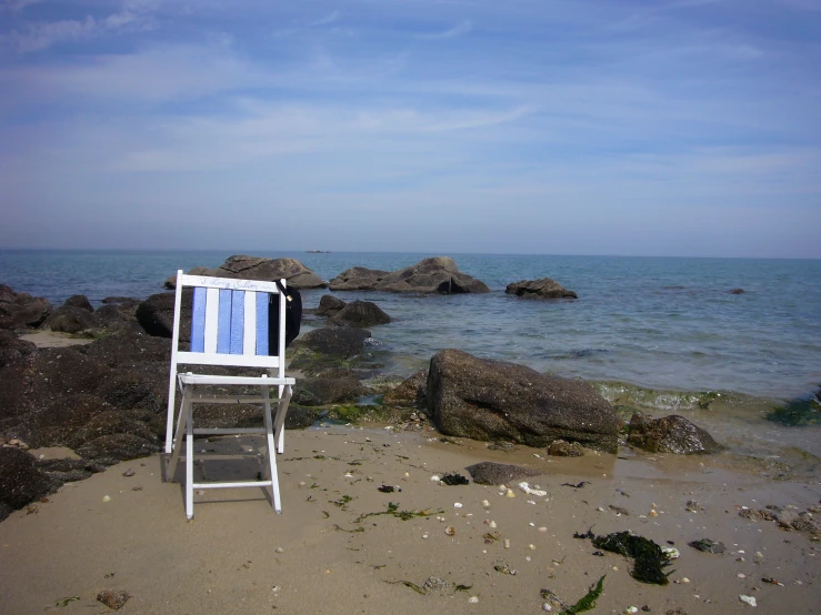 a chair is sitting on the beach by the ocean