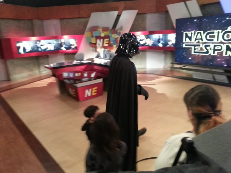 a woman dressed up as darth vader in front of televisions