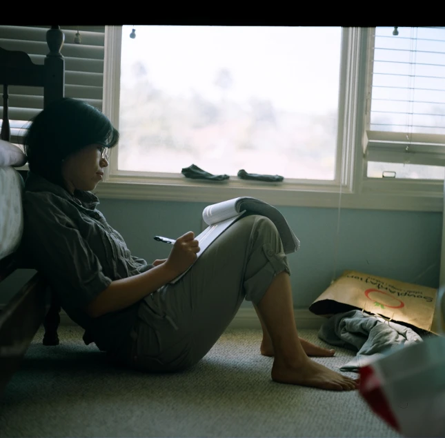 a person reading an article in front of a bed