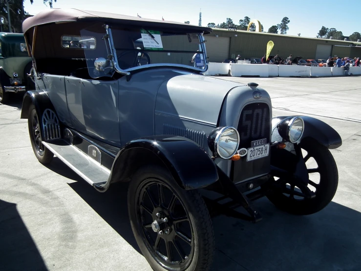 an antique grey car is parked outside on a sunny day