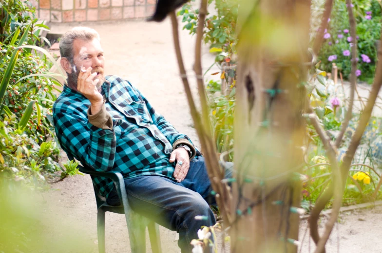 a man with glasses sitting outside on a park bench