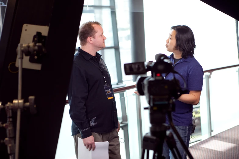 two people talking together next to a camera