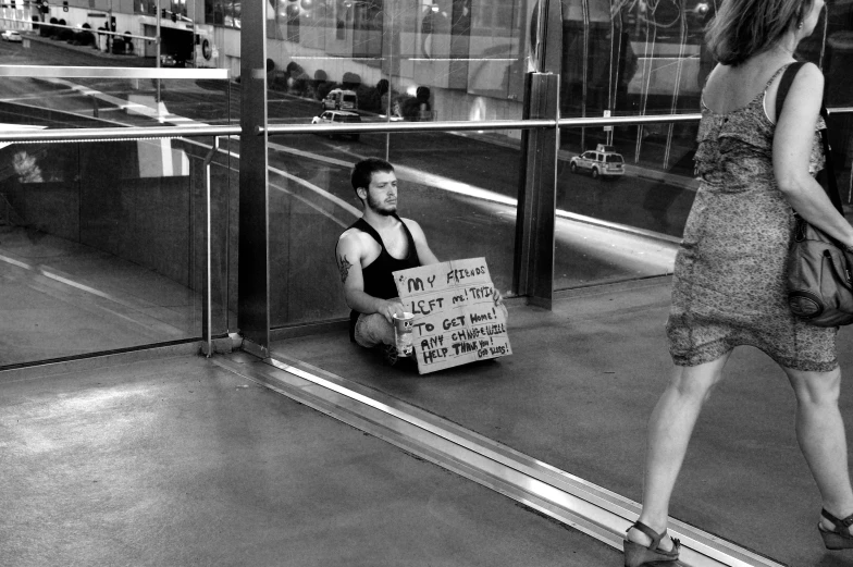 a woman sitting on the ground with a protest sign on her knee