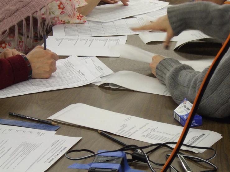 two people sitting at a table covered with papers