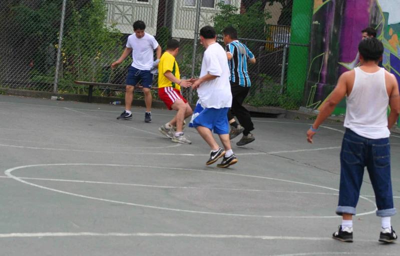 a group of guys playing basketball in an enclosure