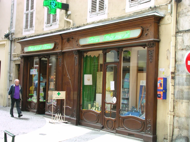 the shopfront of a pharmacy has green lettering on it