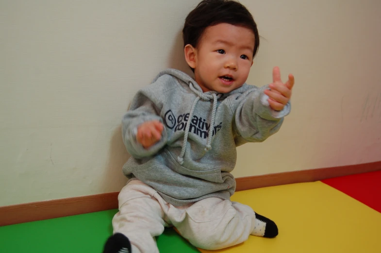 a baby sitting down on a yellow and green mat