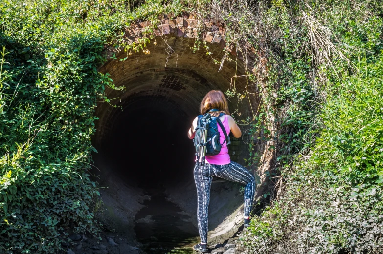 a woman stands at the entrance to a tunnel